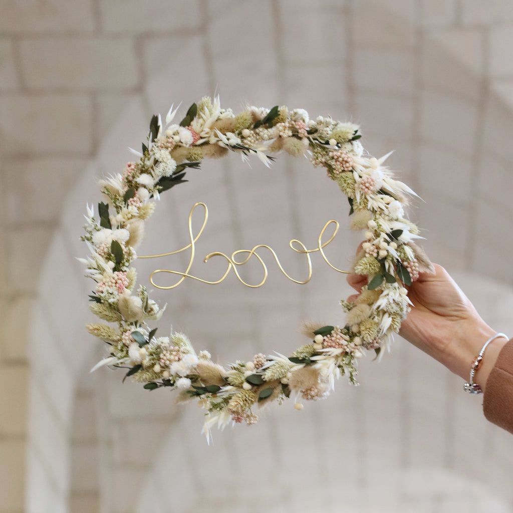 Couronne de fleurs séchées artisanales dans les tons clairs avec une jolie inscription dorée au centre " Love" 